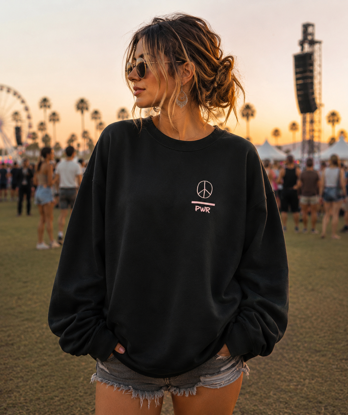 Person wearing a black sweatshirt with a peace symbol at a festival.