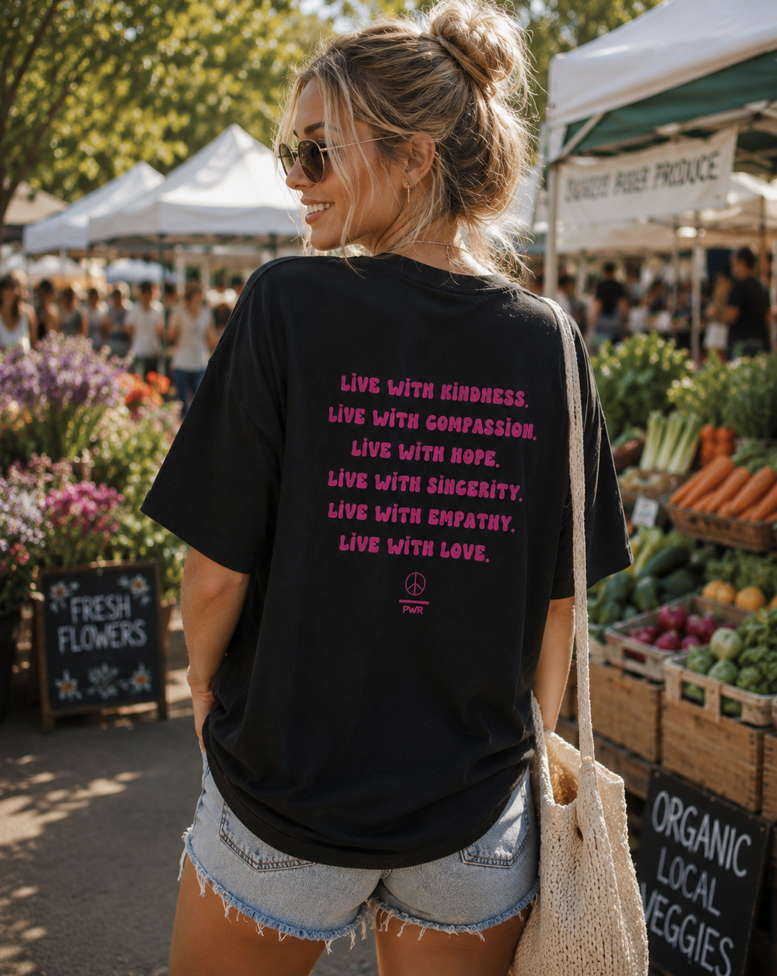Woman at an outdoor market wearing a black t-shirt with motivational text.
