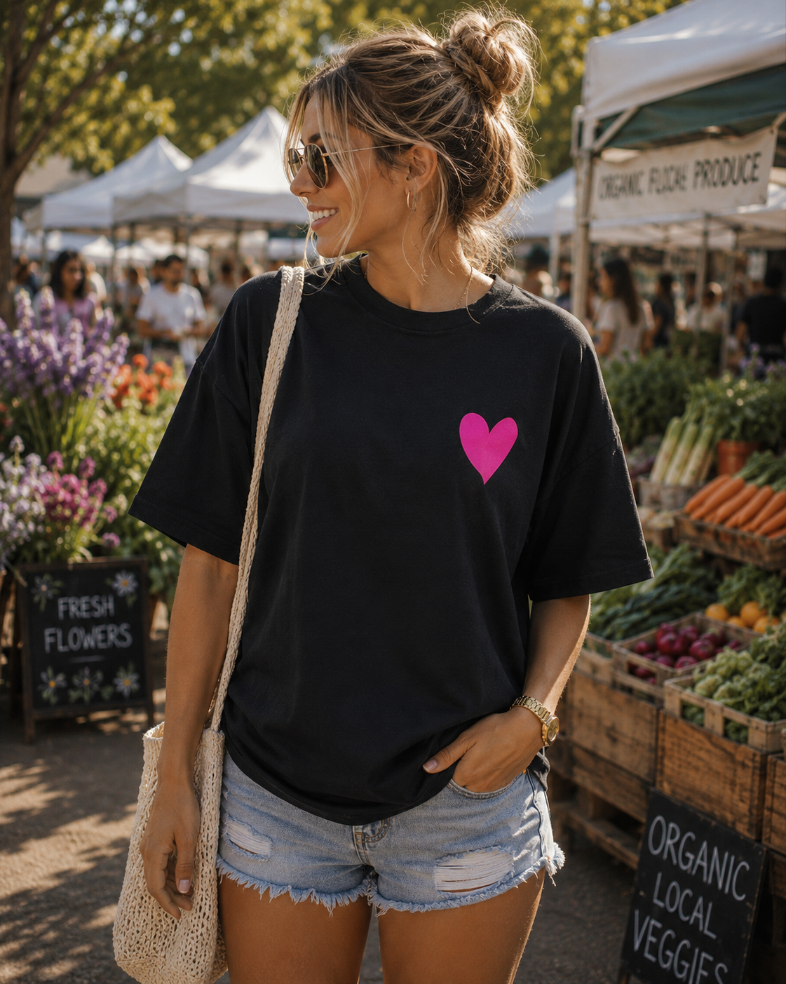 Woman wearing a black t-shirt with a pink heart at an outdoor farmers market.