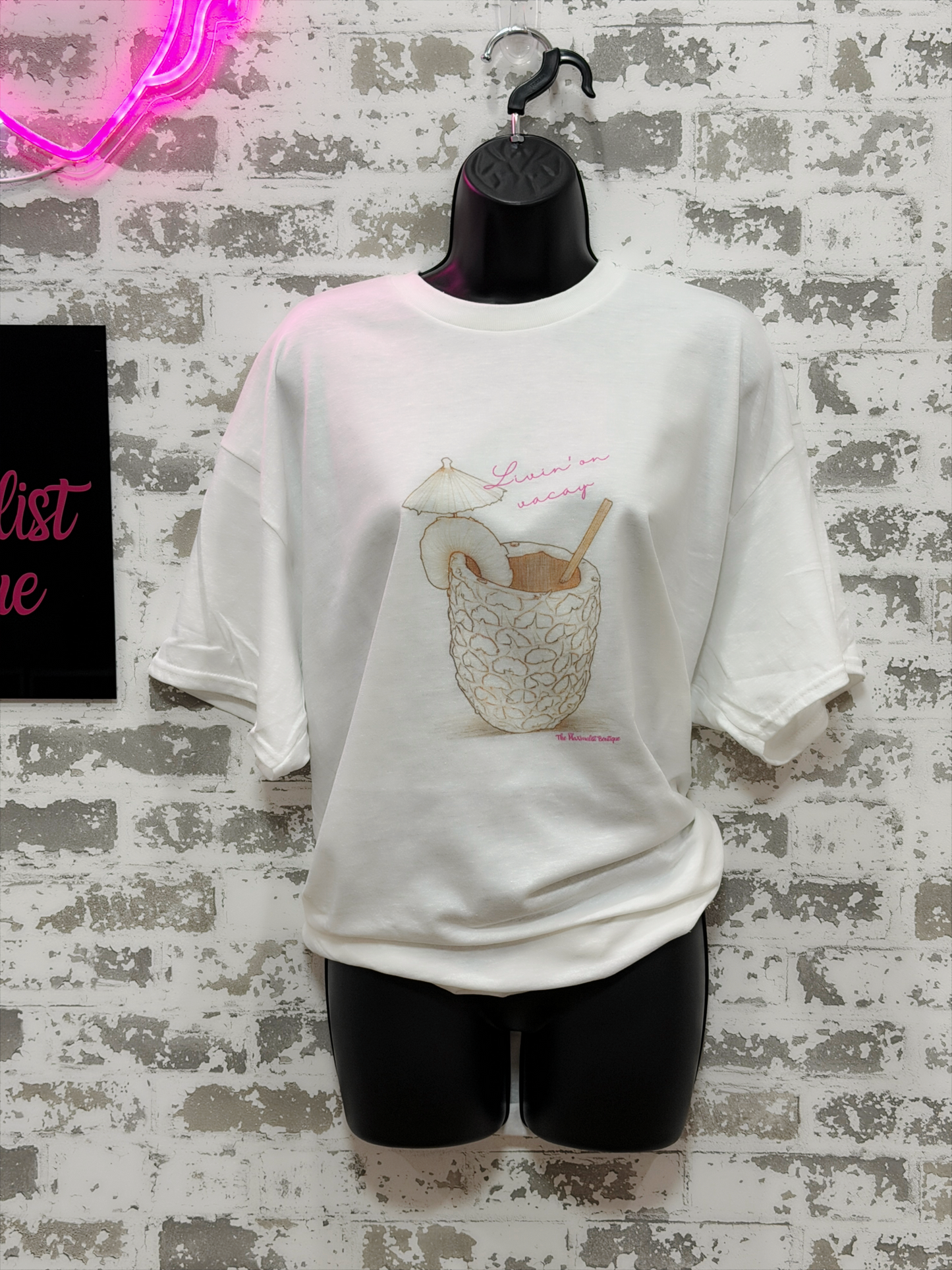 White t-shirt with graphic design on a mannequin against a textured wall.