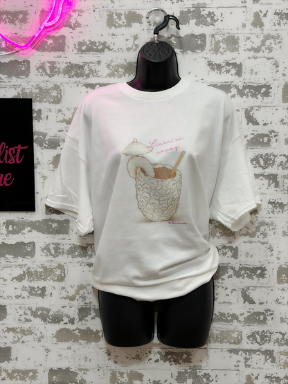 White t-shirt with graphic design on a mannequin against a textured wall.