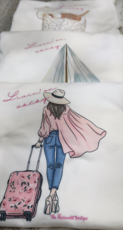 Tee with a design of a woman with a suitcase and text 'Livin on vacay'.