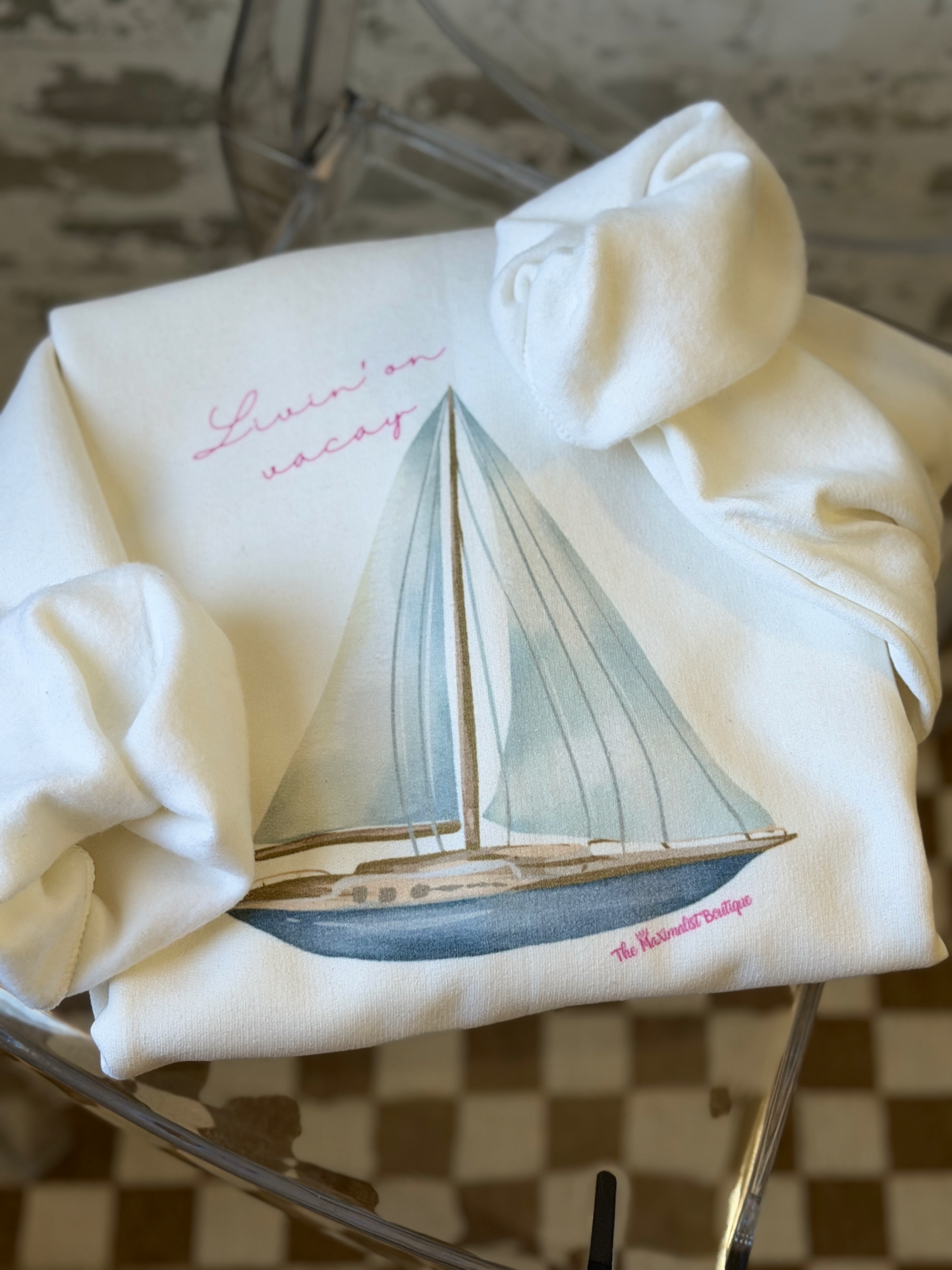 White sweatshirt featuring a sailboat illustration with the phrase “Livin’ On Vacay” across the chest