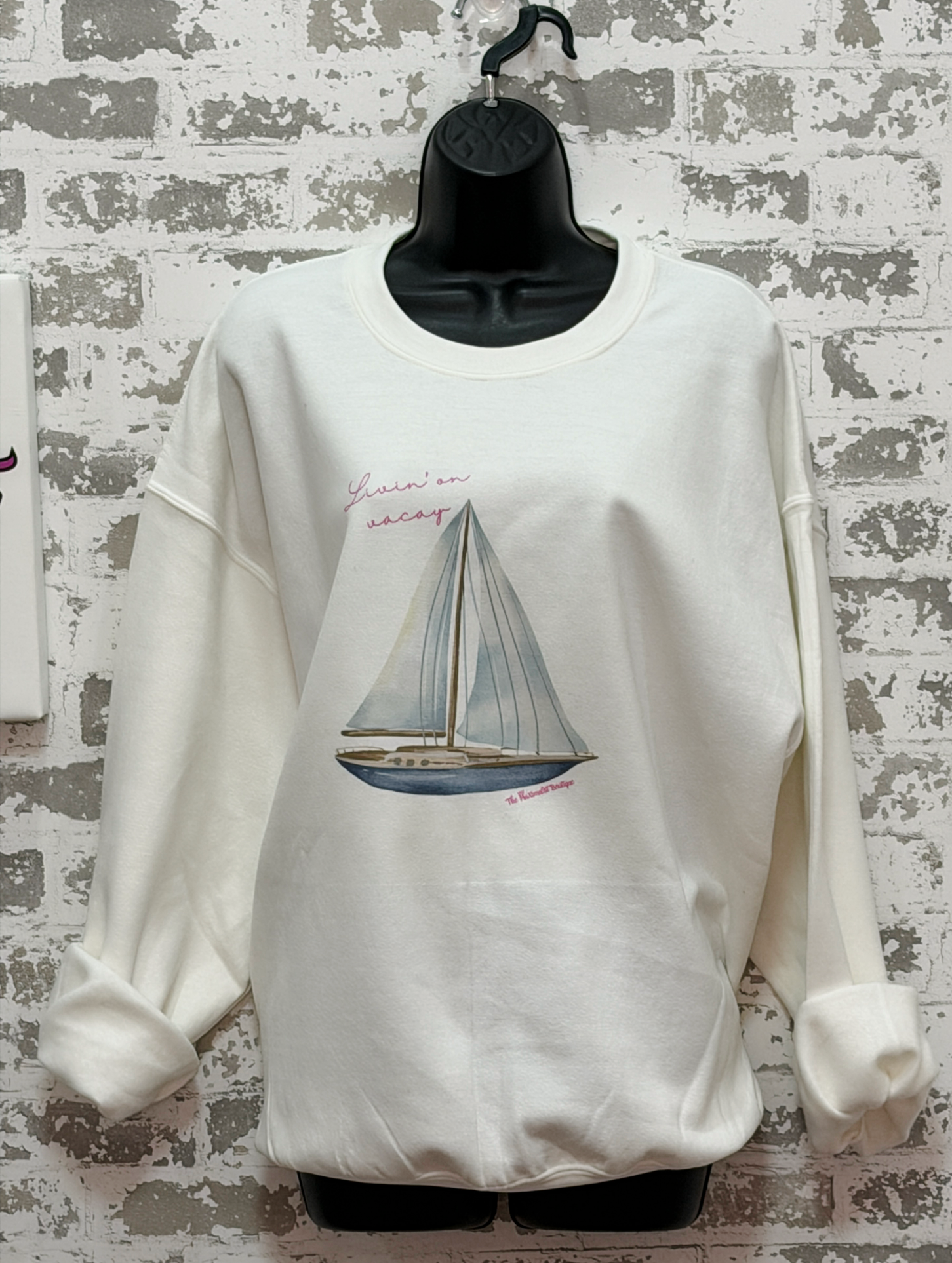 White sweatshirt featuring a sailboat illustration with the phrase “Livin’ On Vacay” across the chest