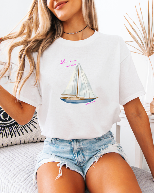 Woman wearing a white t-shirt with a sailboat graphic and text, sitting on a couch.