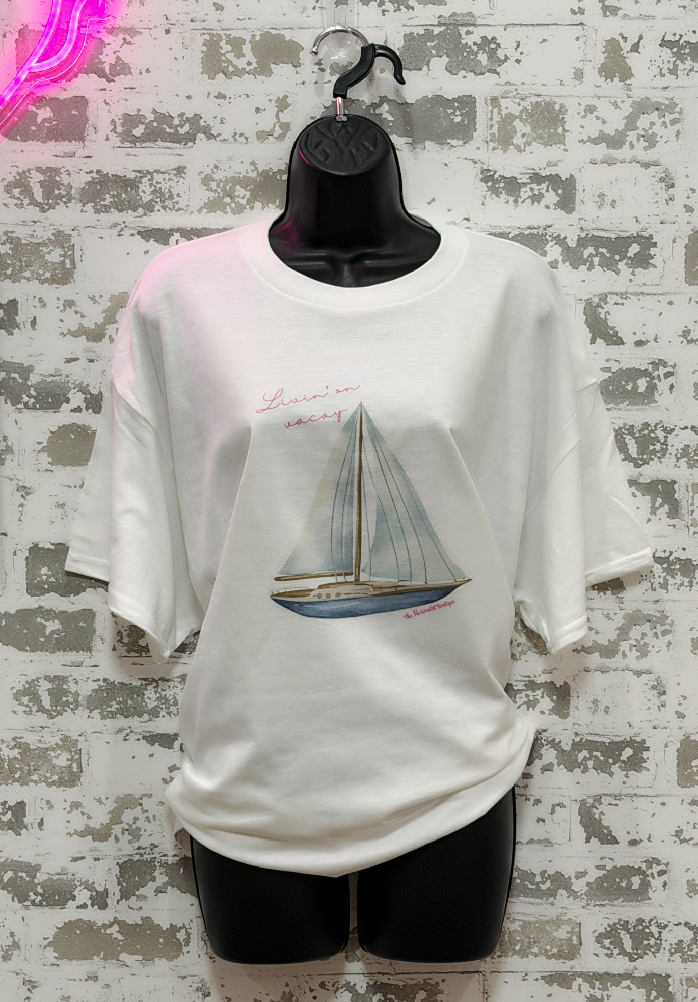 White t-shirt with sailboat design on a textured wall background