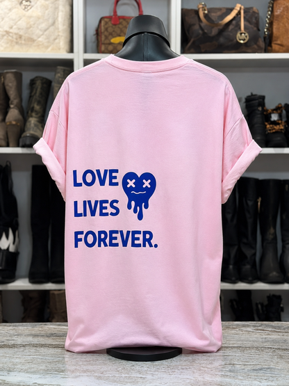 Pink t-shirt with 'Love Lives Forever' text and graphic on a mannequin in front of a shoe rack.