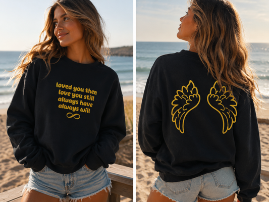 Woman wearing a black sweatshirt with GOLD text and graphics on a beach.