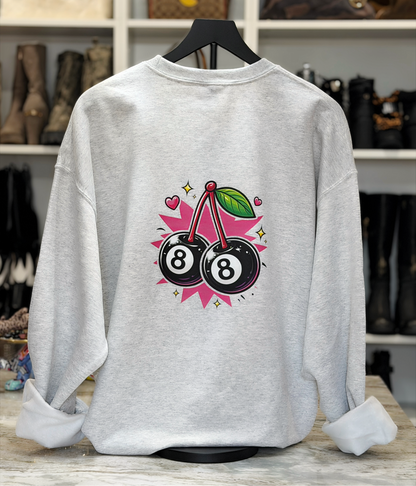 Gray sweatshirt with 8-ball and cherry design on a hanger against a shoe store background