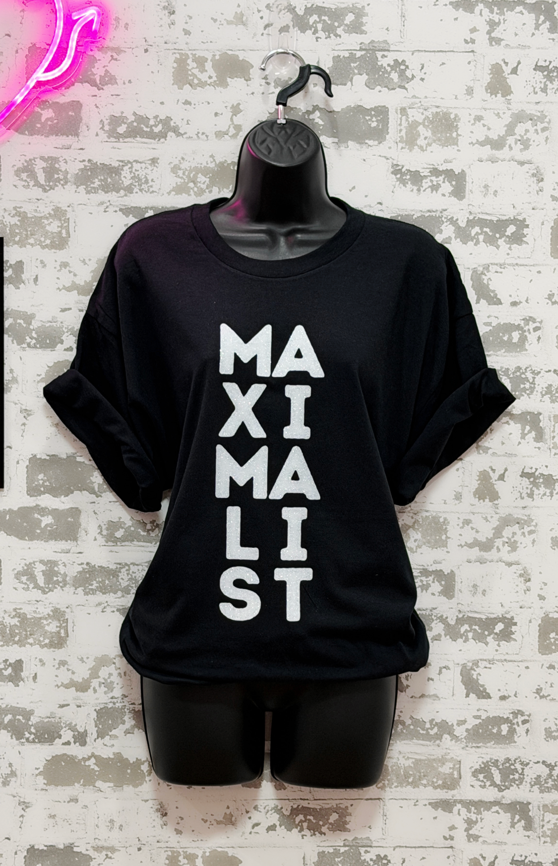 Black t-shirt with 'MAXIMALIST' text on a textured wall background