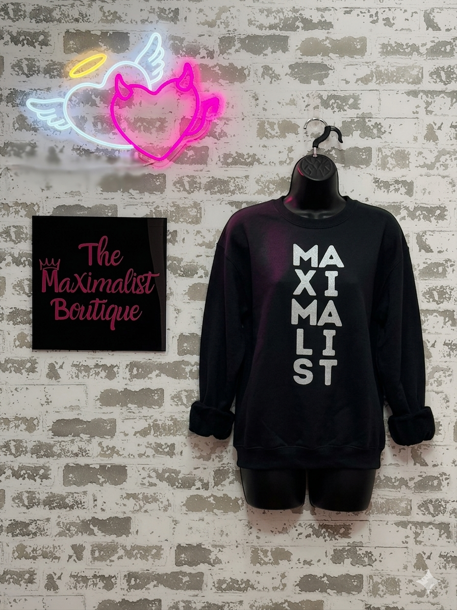 Black sweatshirt with 'MAXIMALIST' text, neon sign, and 'The Maximalist Boutique' sign on a textured wall.