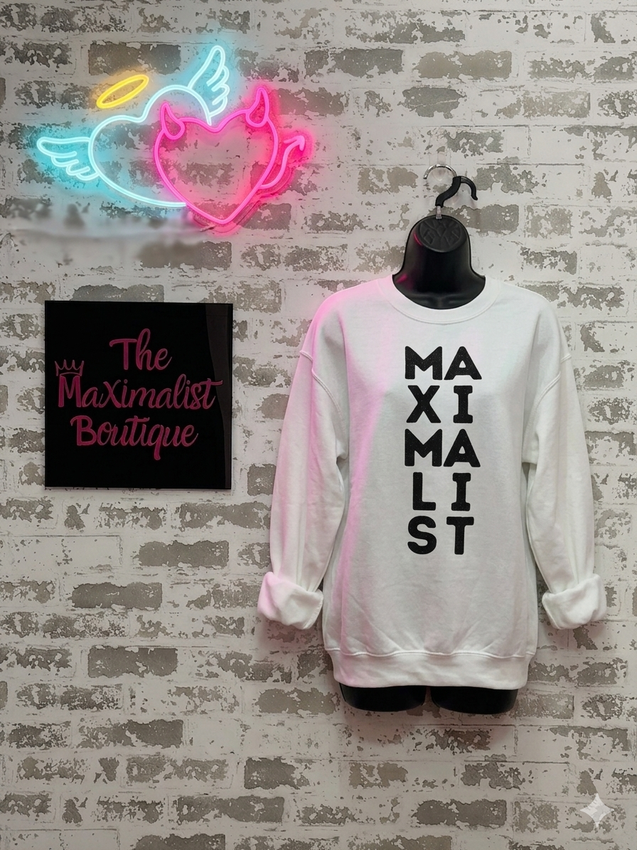 White sweatshirt with 'MAXIMALIST' text, neon sign, and 'The Maximalist Boutique' sign on a textured wall.