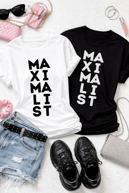Two t-shirts, one white and one black, with 'MAXIMALIST' text, displayed with accessories on a light surface.