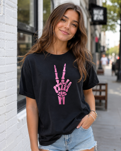 Woman wearing a black t-shirt with a pink skeleton hand design on a city street.