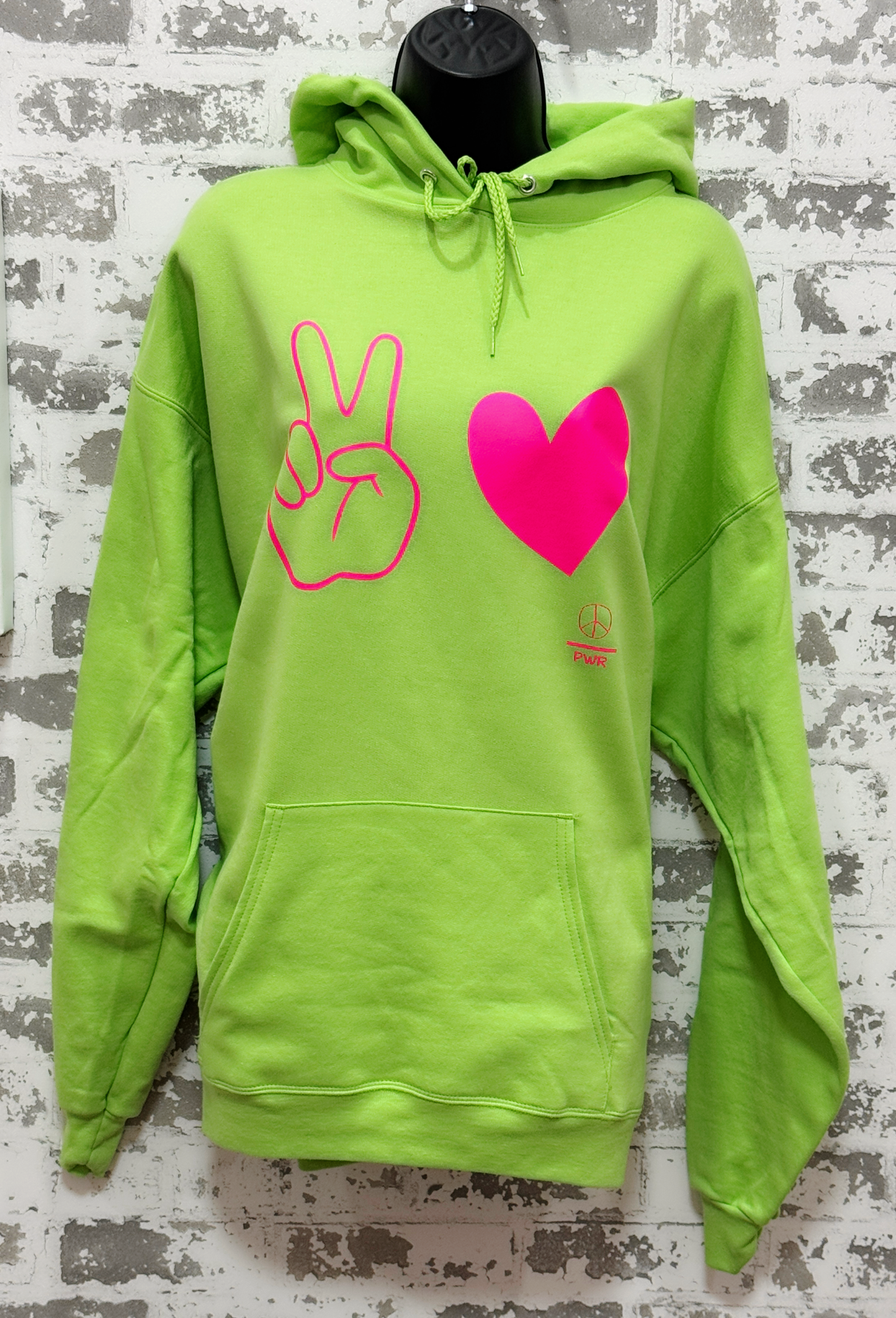 Green hoodie with peace sign and heart design on a textured gray background
