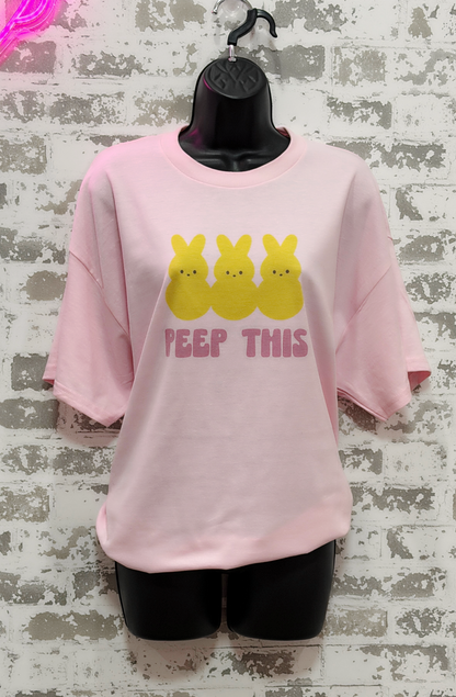 Pink sweatshirt with yellow characters and 'PEEP THIS' text on a textured wall background