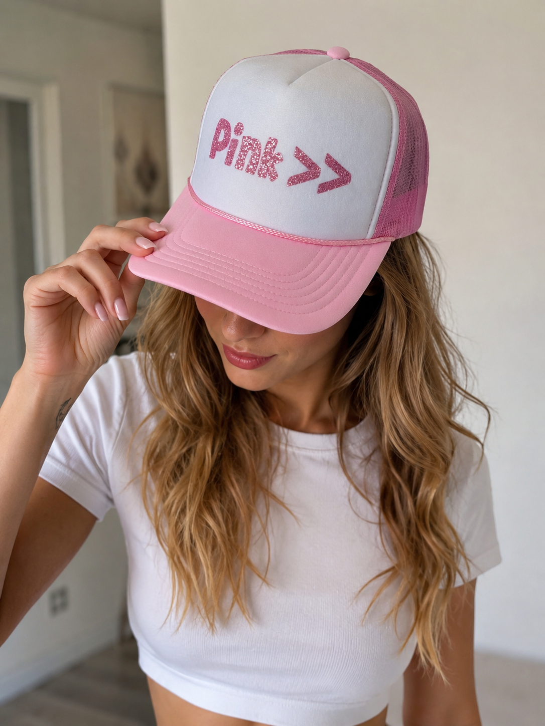 Person wearing a pink and white cap with 'Pink' text, indoors.