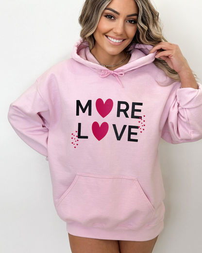 Woman wearing a pink hoodie with 'More Love' text and hearts on a white background