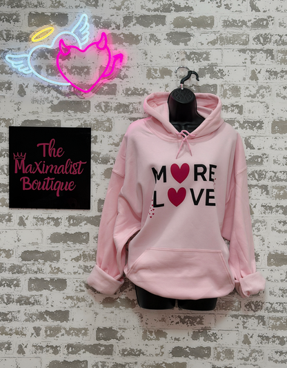 Light pink hoodie with black “MORE LOVE” lettering and pink heart graphics