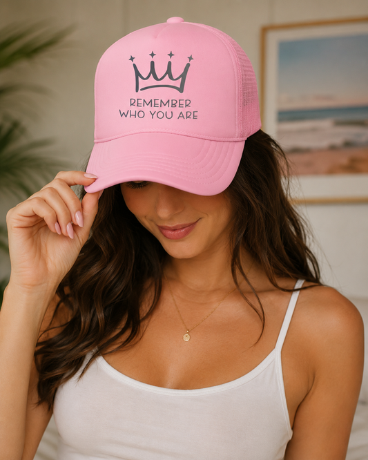 Woman wearing a pink cap with 'Remember Who You Are' text and logo.