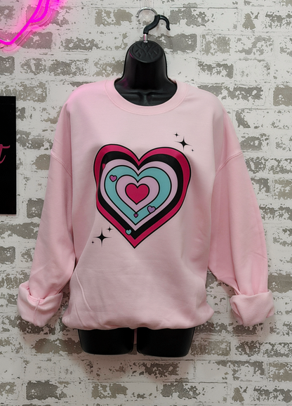 Pink sweatshirt with a colorful heart design on a textured gray background