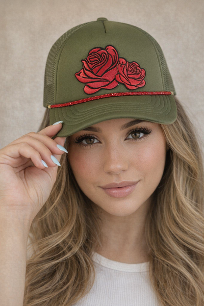 Woman wearing a green cap with red rose design against a neutral background