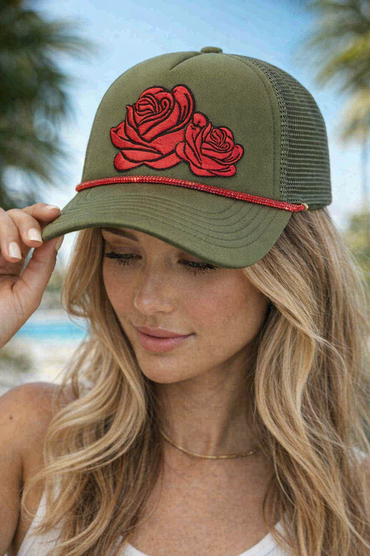 Woman wearing an olive green cap with red rose designs against a blurred natural background