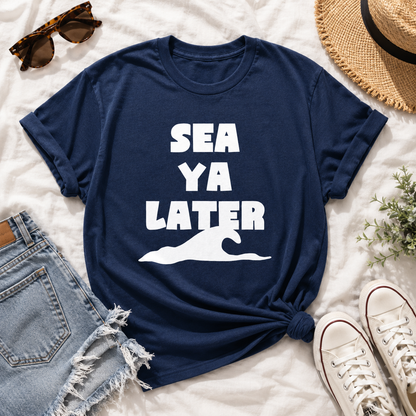 Navy blue t-shirt with 'SEA YA LATER' text and graphic on a white surface with sunglasses, hat, and sneakers.