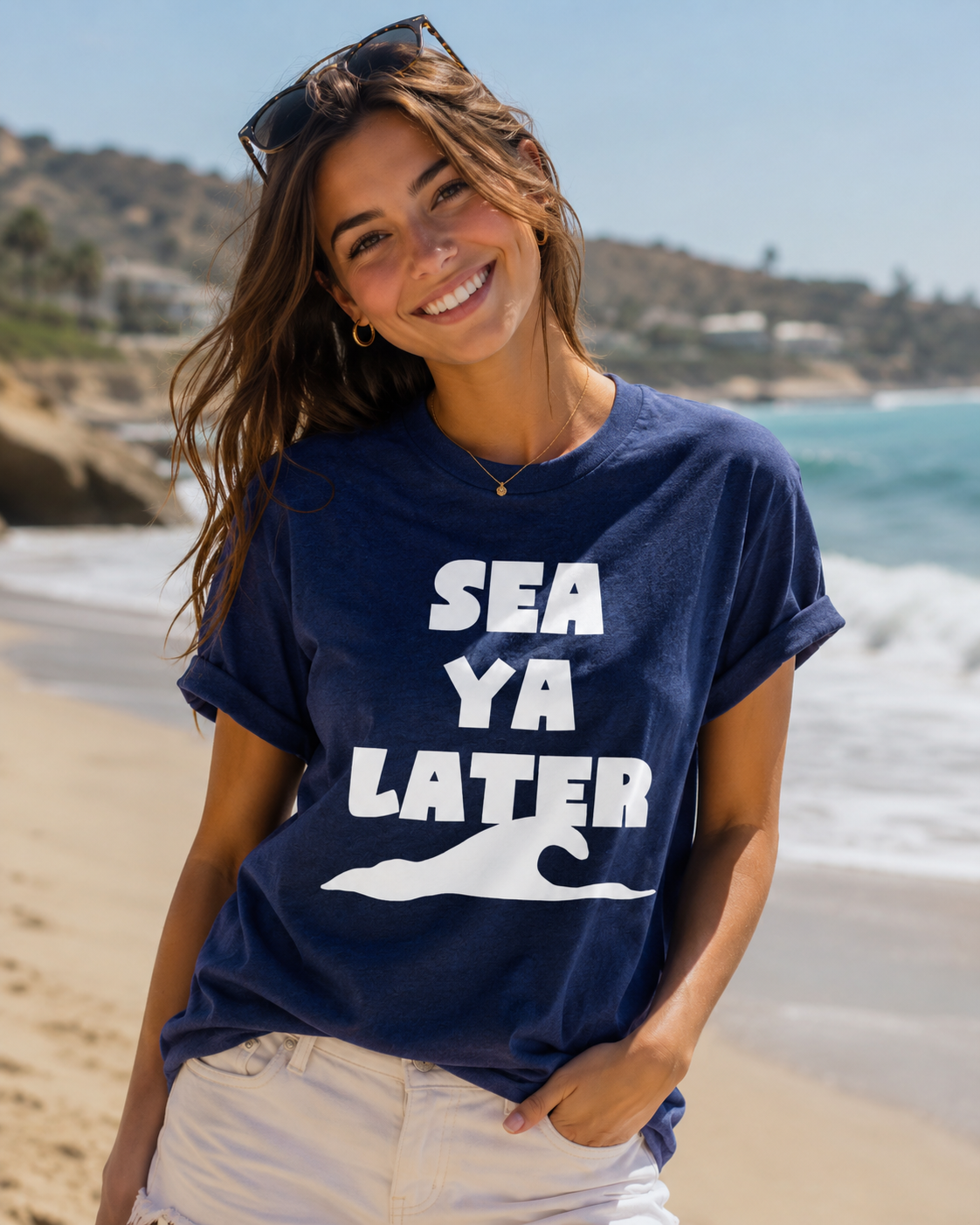 Woman wearing a navy blue t-shirt with 'SEA YA LATER' text on a beach.