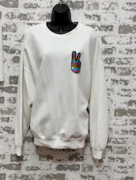 White sweatshirt with a colorful peace sign patch on a textured gray background