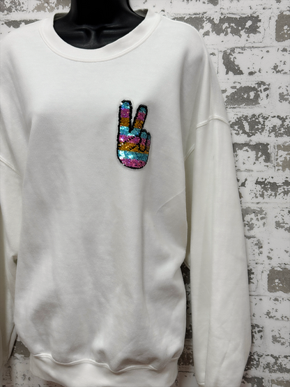 White sweatshirt with a colorful peace sign patch on a textured wall background