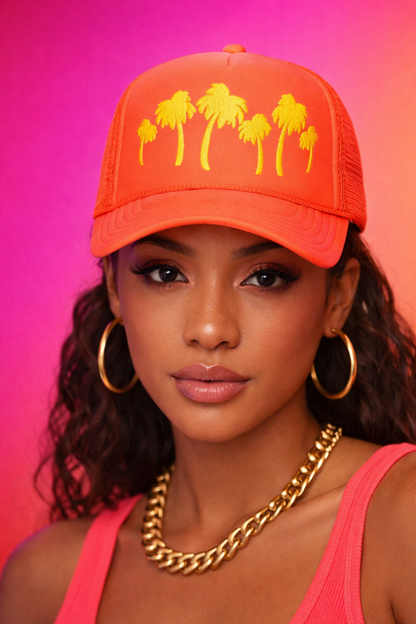 Woman wearing an orange cap with palm tree designs on a pink background