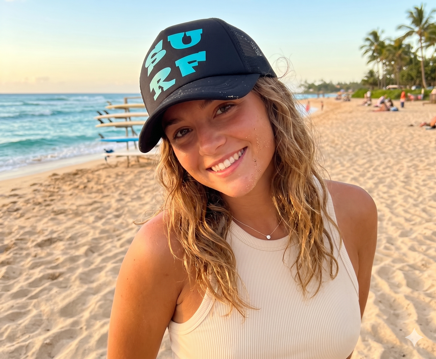 Woman wearing a 'Surf' cap on a beach with palm trees and ocean in the background