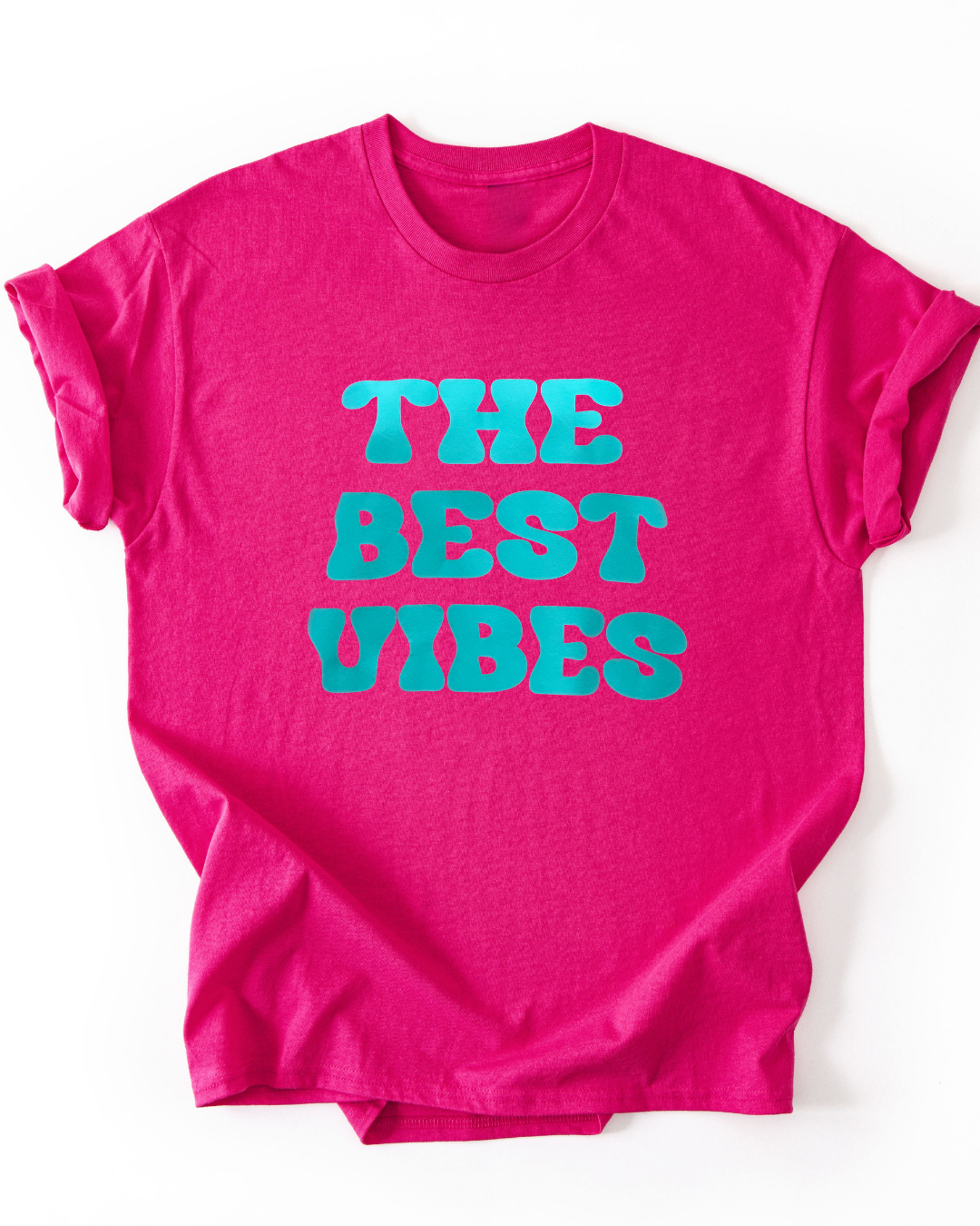 Pink t-shirt with 'THE BEST VIBES' text in turquoise on a white background