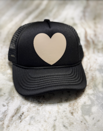 Black cap with a beige heart on a marble surface