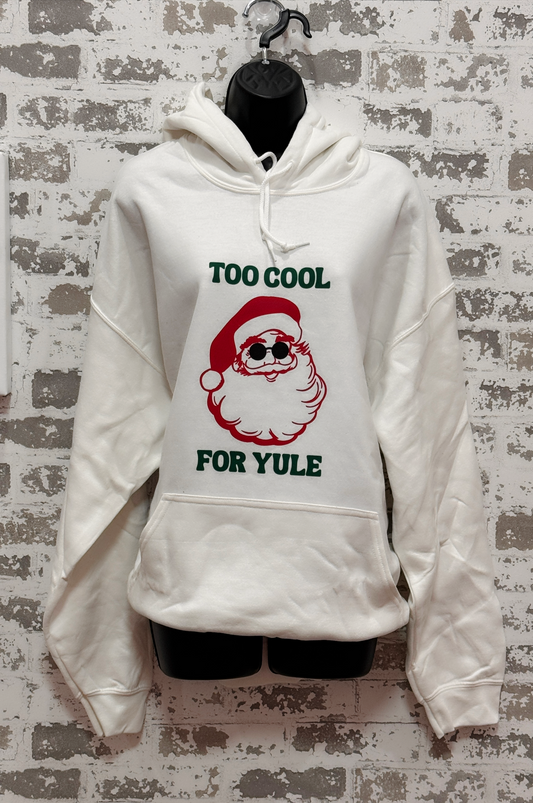 White hoodie with Santa Claus graphic and text 'Too Cool for Yule' on a textured wall background