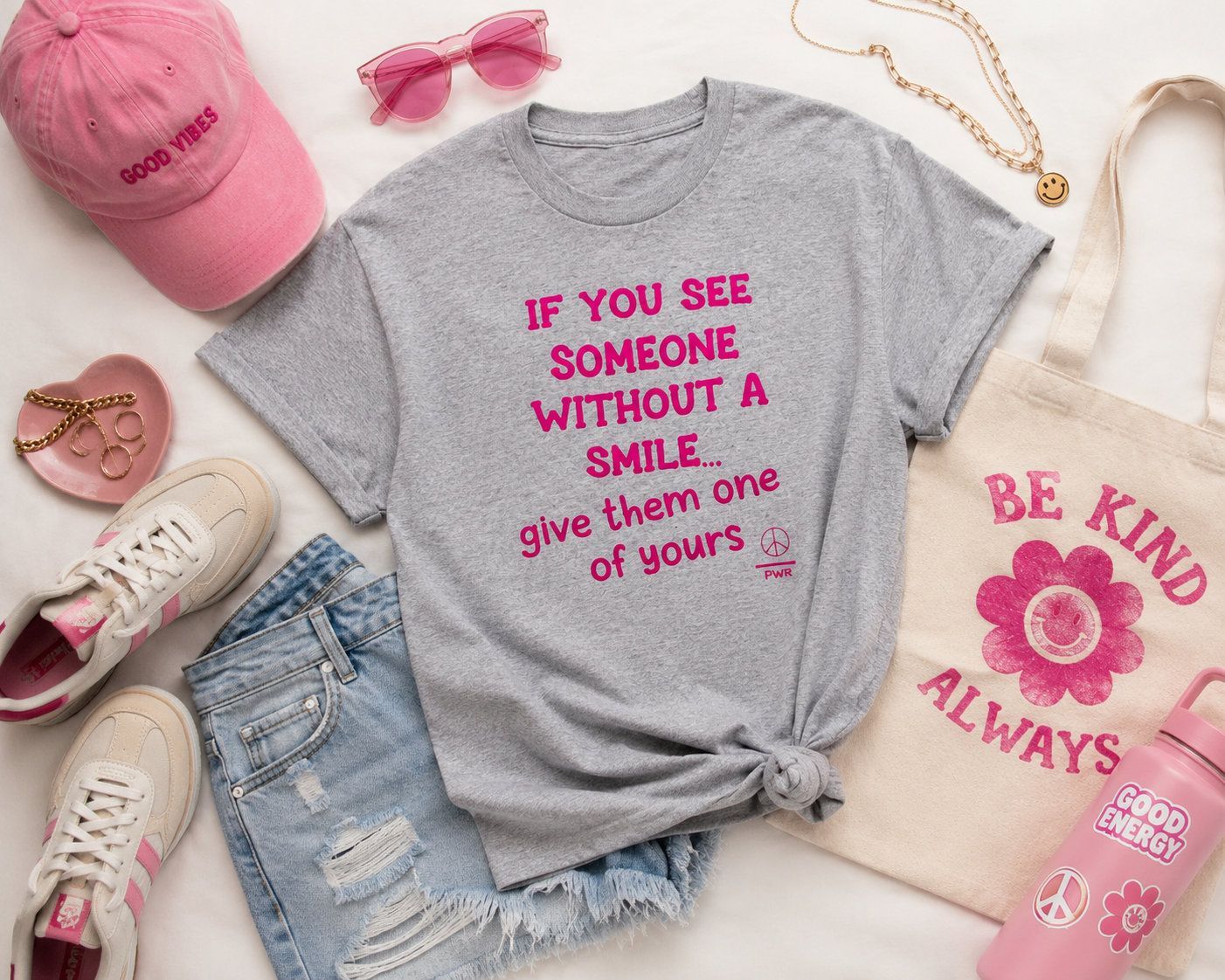Gray t-shirt with pink text, pink cap, denim shorts, sneakers, and pink water bottle on a white background.
