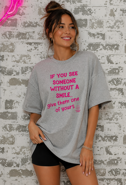 Woman wearing a gray t-shirt with pink text against a textured wall.