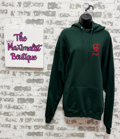Green hoodie with red logo on a hanger against a textured wall with 'The Maximalist Boutique' sign.