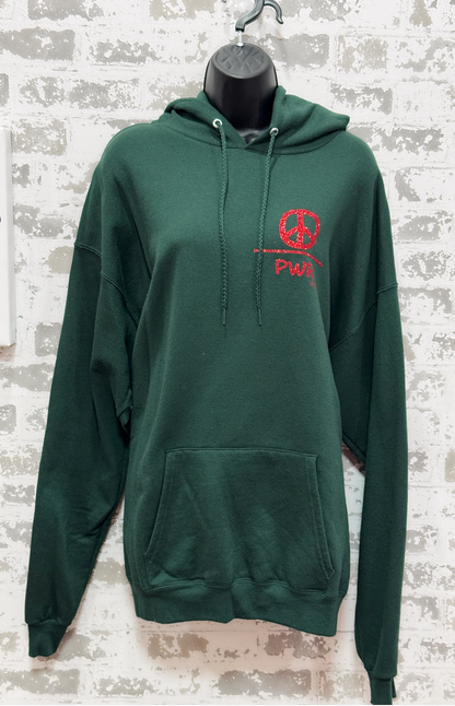 Green hoodie with red peace symbol design on a textured white brick wall background