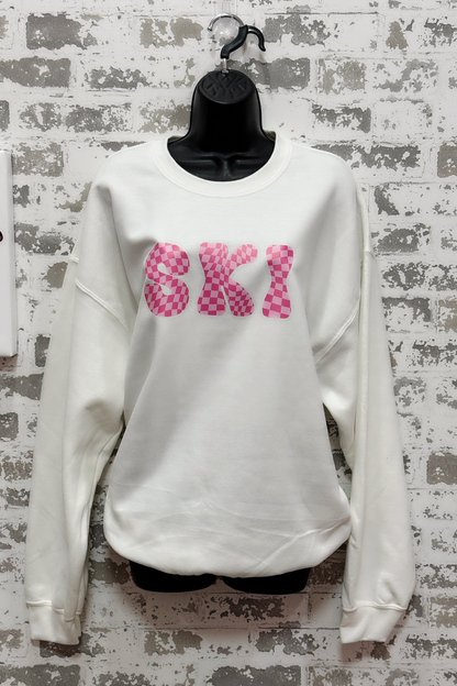 White sweatshirt with pink 'SKI' text on a textured wall background