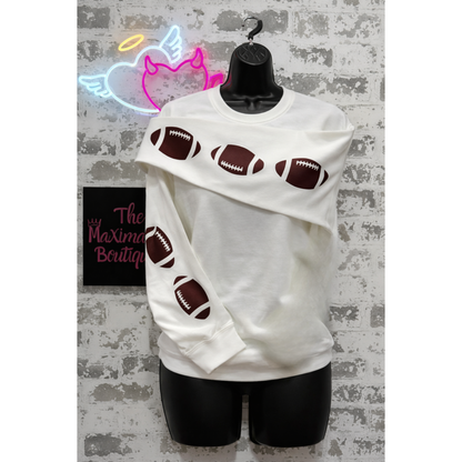 White hoodie with football designs on a mannequin against a textured wall with neon sign.